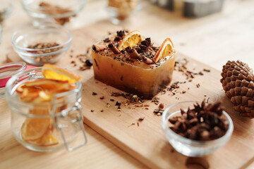 Large soap bar with cinnamon sticks, star anise and orange slices on board