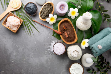 Beautiful spa relax concept. Coffee with cinnamon scrub, green tea scrub, cotton pouches with herbs for massage, sea stones and other Spa accessories on grey table top view. Copy space.