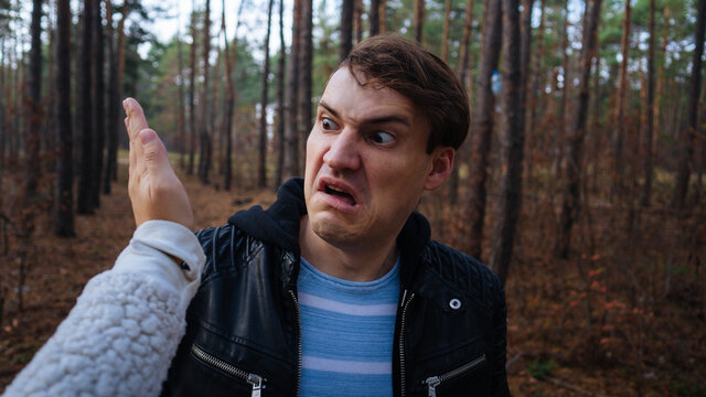A woman's hand hits a man's face in the autumn forest. An emotional male is getting slapped in face, while shouting in a fear.