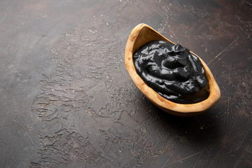 Dead sea mud in a bowl of olive wood on a dark background. Copy space