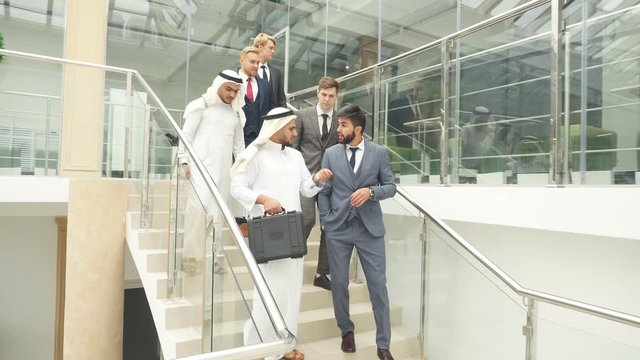 Handsome caucasian man in tuxedo talk about business idea to sheikh in white suit