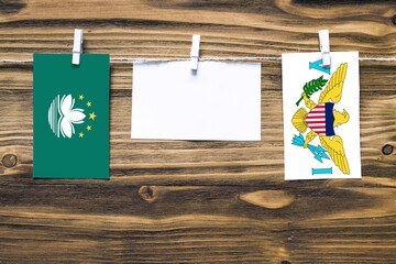 Hanging flags of Macao and United States Virgin Islands attached to rope with clothes pins with...