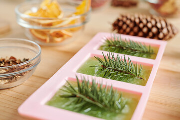 Handmade green soap with conifer and glassware with aromatic ingredients