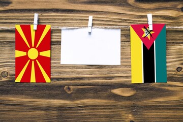Hanging flags of Macedonia and Mozambique attached to rope with clothes pins with copy space on...