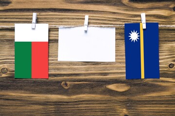 Hanging flags of Madagascar and Nauru attached to rope with clothes pins with copy space on white...