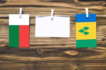 Hanging flags of Madagascar and Saint Vincent And The Grenadines attached to rope with clothes pins...