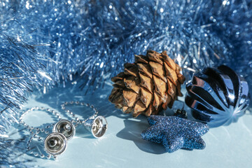 Christmas toys: silver bells, blue shiny star, wavy ball, pine cone and tinsel smoothly fading into...