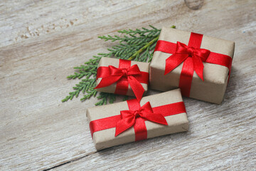 Some gift boxes wrapped in brown craft paper and tie red satin ribbon. Decorative wooden background. Your text space. Set of presents.	