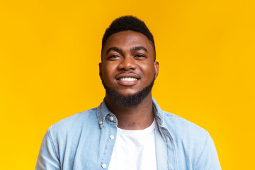 Portrait of confident black millennial guy over yellow background