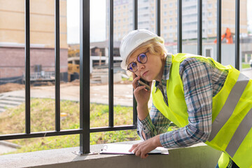 A female builder worker at a construction site works and controls the process.