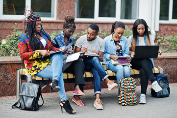 Group of five african college students spending time together on campus at university yard. Black...