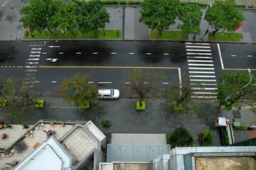 View from inside window of building next to the road, Looking down wet floor street and footpath in front of hotel in Vietnam, Top view entrance and rooftop of building.