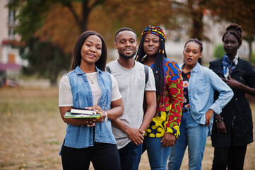 Row of group five african college students spending time together on campus at university yard. Black afro friends studying. Education theme.