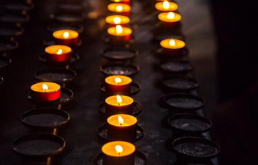 Prayer burning candles in a church on a dark background. Religious concept.