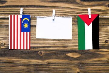 Hanging flags of Malaysia and Palestine attached to rope with clothes pins with copy space on white...