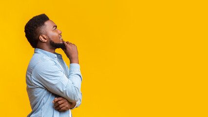 Black millennial man thinking about something and looking upwards