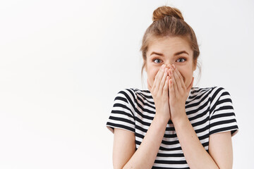 Close-up surprised, astonished speechless good-looking woman in striped t-shirt with messy bun, cover mouth as reacting silly and amazed to awesome gift, stand white background