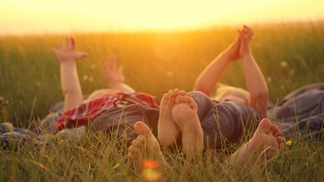 Two happy children, a boy and a girl, lie on the green grass on a summer day. Hands close up.