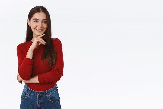 Girl thinking about interesing concept, have good idea. Attractive brunette woman in red blouse, touching chin and smiling sly, having creative plan, standing thoughtful or pensive, white background