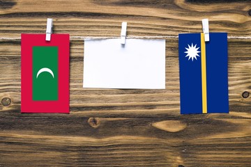 Hanging flags of Maldives and Nauru attached to rope with clothes pins with copy space on white...