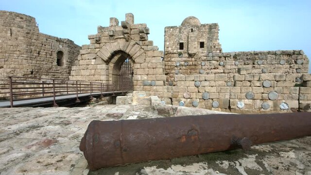 Pan left to the entrance of Sidon Sea Castle, Lebanon. Old canon in foreground