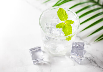 glass of water soda with ice and mint on green background