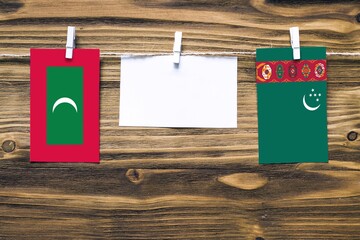 Hanging flags of Maldives and Turkmenistan attached to rope with clothes pins with copy space on...