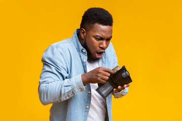 Shocked african american guy holding wallet with dollar cash
