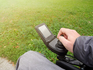 Close up of a disabled person hand driving electric wheelchair using joystick © 24K-Production
