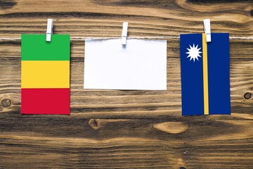 Hanging flags of Mali and Nauru attached to rope with clothes pins with copy space on white note...