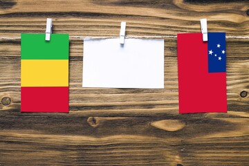Hanging flags of Mali and Samoa attached to rope with clothes pins with copy space on white note...