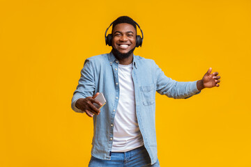 Cheerful guy in headphones listening music on smartphone and dancing