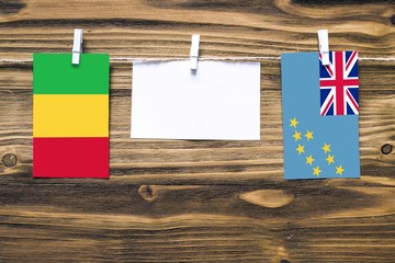 Hanging flags of Mali and Tuvalu attached to rope with clothes pins with copy space on white note...