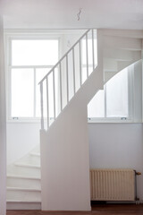Old staircase in a white hall with windows