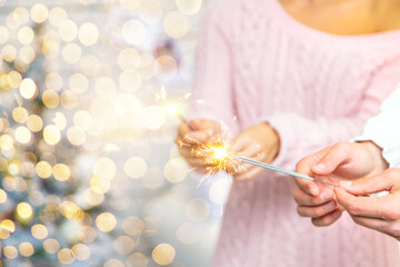 Christmas sparklers in the hands of a man and a woman. Holiday. Selective focus.