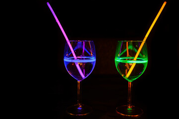 Mocktail wine glass filled with garnished refreshing alcohol liquid and colorful straw with black background for nightlife party restaurant
