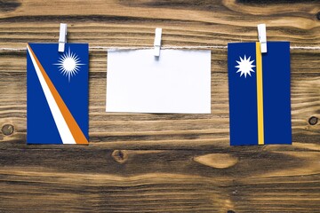 Hanging flags of Marshall Islands and Nauru attached to rope with clothes pins with copy space on...