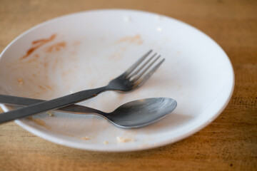 Dirty plate with spoon and fork after a meal