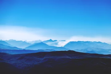 Rolgordijnen Caucasian ridge. Mountain blue landscape. Clouds over the valley © Amina