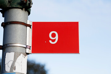 the nine digit with white text on red plate background hangs like a sign on lamppost
