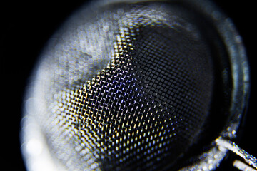 a tea strainer in close-up against black background