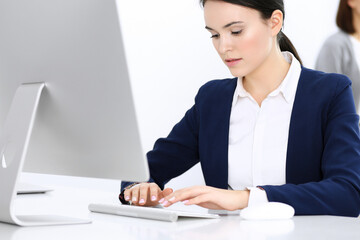 Business woman working with computer in office, female colleague at background. Headshot of Lawyer or accountant at work while sitting at the desk
