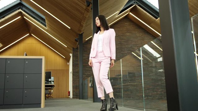 Trendy businesswoman filmed in bullet time, walking through office & posing at camera