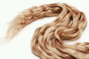 Light brown wavy human hair on white background. Beauty salon. Hair Extensions.