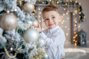 little boy decorates a Christmas tree for Christmas