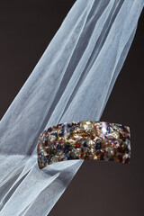 Object shot of a big hairpin, lying on a dark brown background. The hairpin is decorating with...
