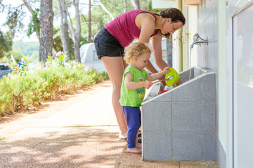 Mother and daughter dish wasing together outdoor.