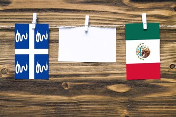 Hanging flags of Martinique and Mexico attached to rope with clothes pins with copy space on white note paper on wooden background.Diplomatic relations between countries.