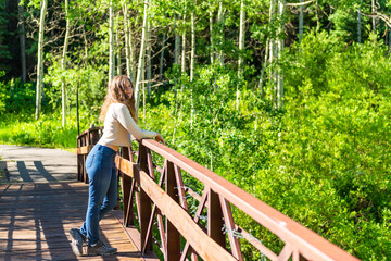 Snowmass village Aspen town with young happy woman leaning on wooden bridge and nobody in summer view at Brush Creek trail in Colorado downtown