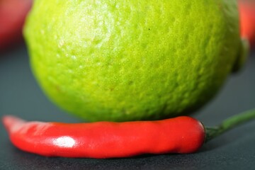 bright green lime and red pepper on black background